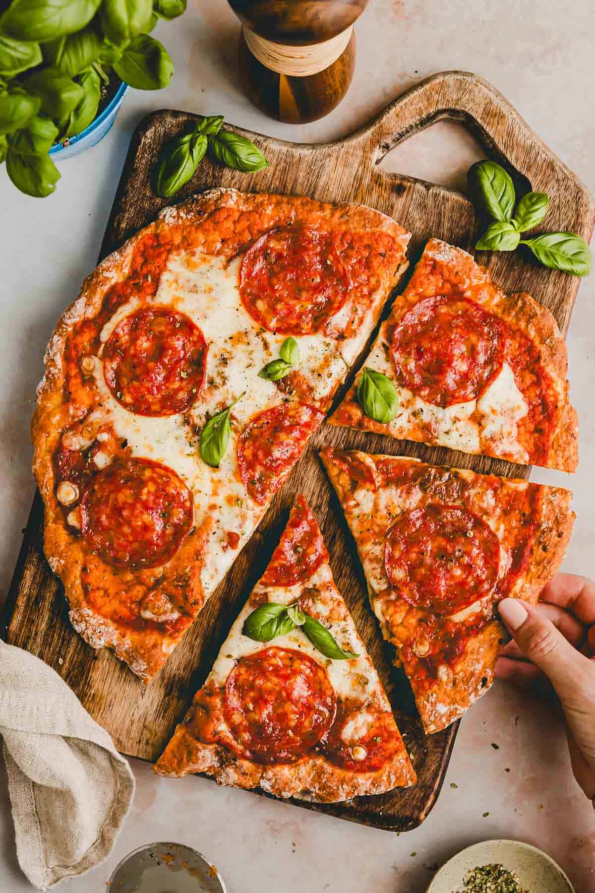 high protein cottage cheese pizza with pepperoni in slices on a wooden board